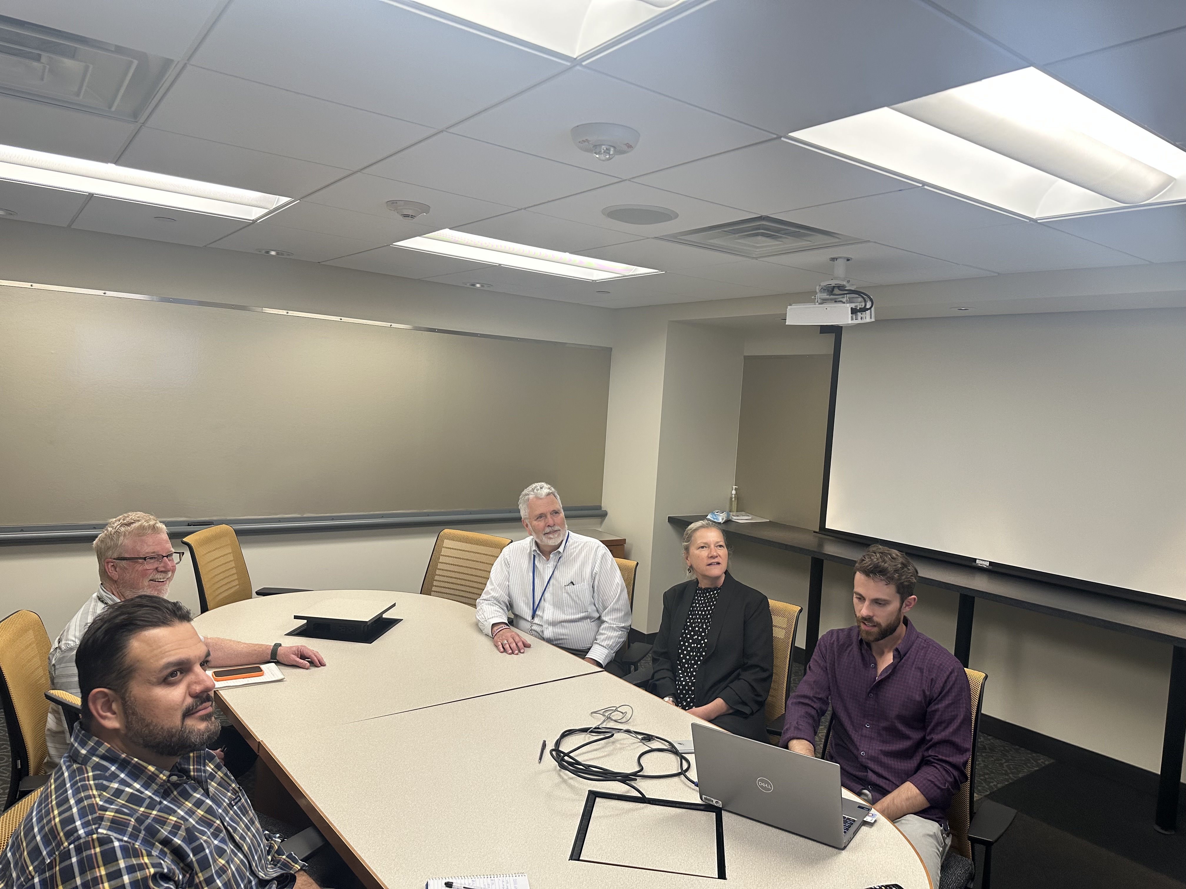 Staff seated in a meeting room during virtual session.