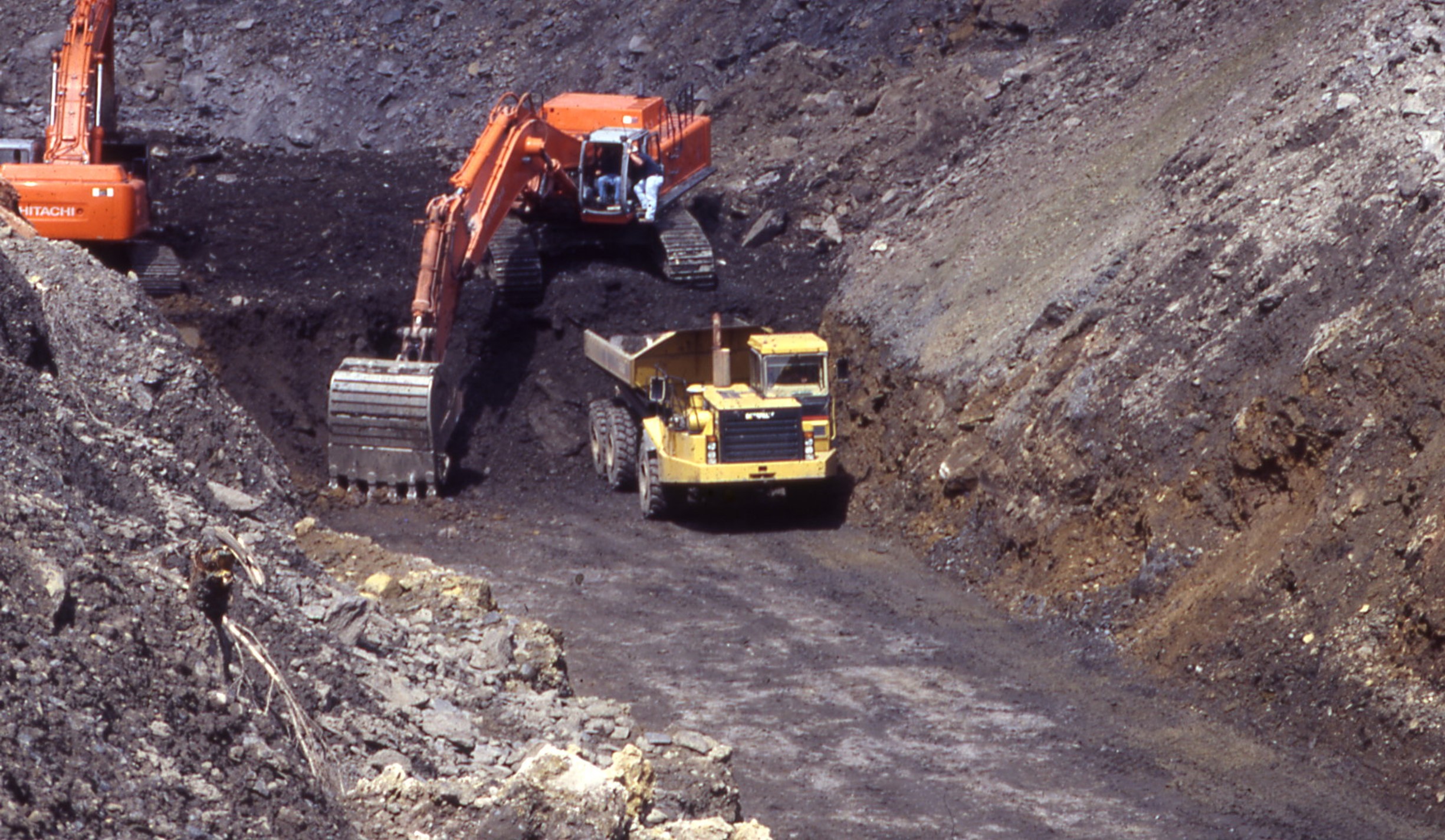 This image shown an excavator filling a dump truck with materials excavated from the trench.  This image was taken during the Olyphant Project where a cutoff trench was installed to prevent the fire from advancing further into the coal seam.  The trench was successful in stopping the progress of the mine fire and allowed for the rest of the fire to be excavated and extinguished.