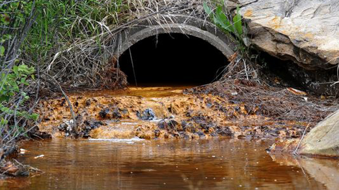 Orange acid mine drainage flows from a pipe