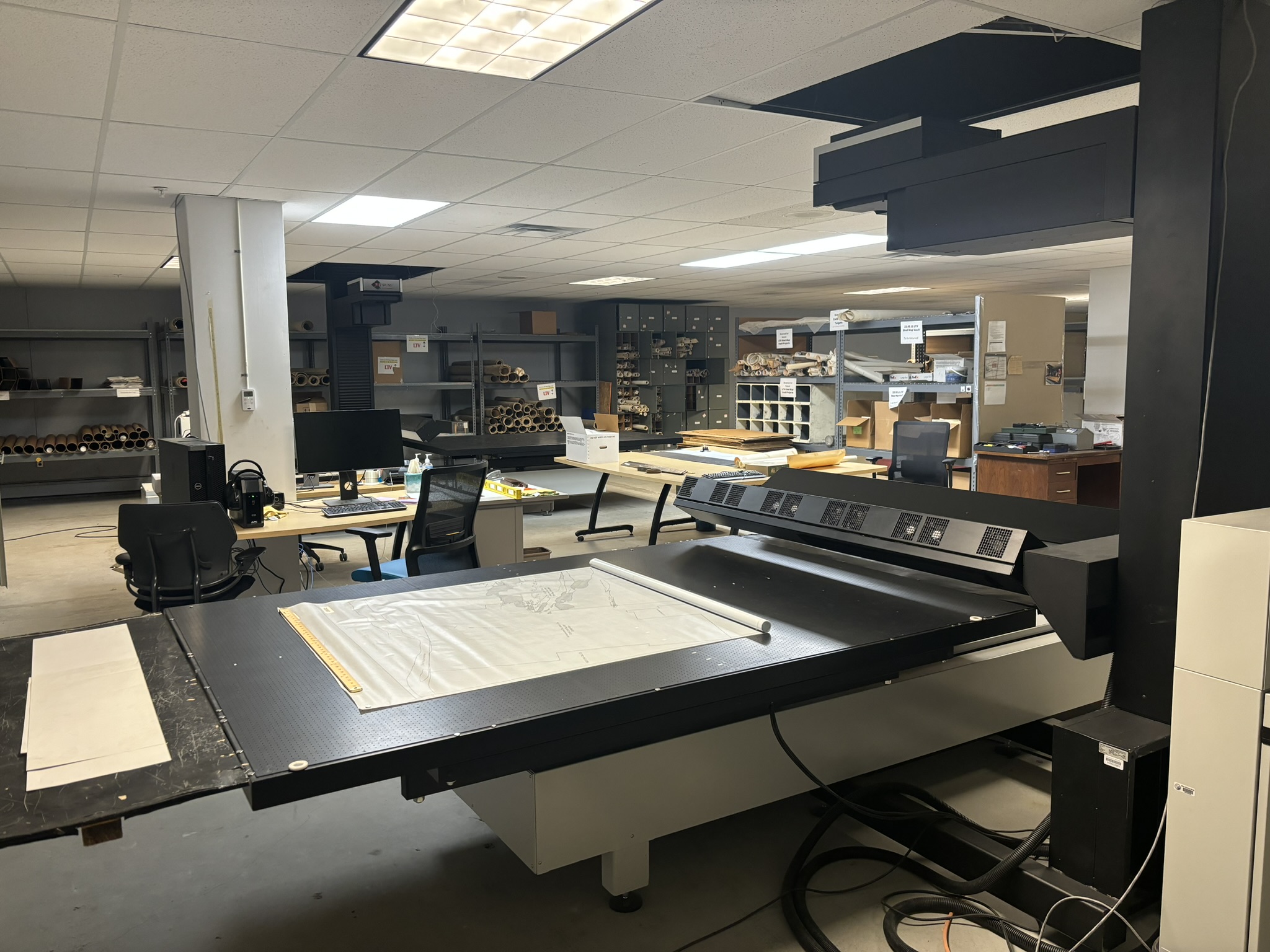 Photo of a large flatbed scanner with a map halfway unrolled on top.