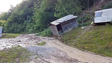 A small building leans down a landslide area with mudflow beneath