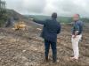 DOI Officials standing and pointing on a mine site with equipment in the background