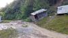 A small building leans down a landslide area with mudflow beneath